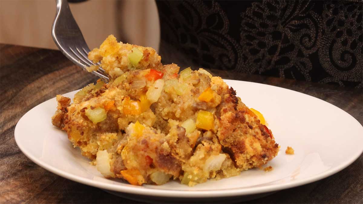 sausage and cornbread stuffing on a white plate with fork