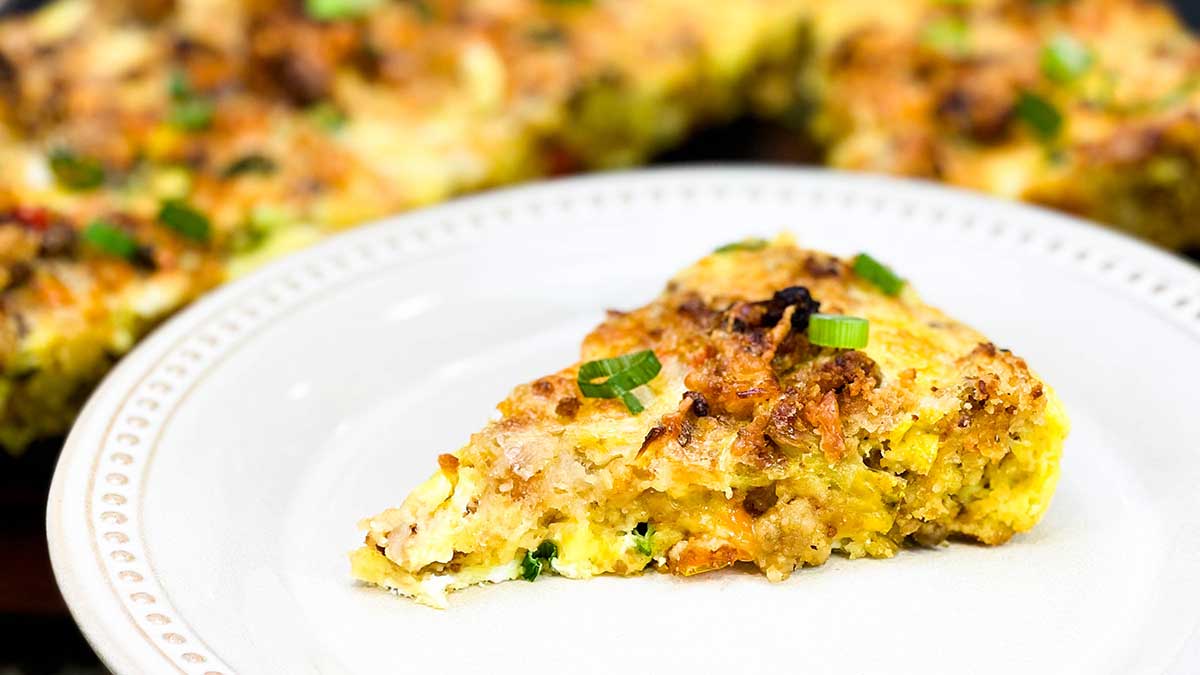 Slice of stuffing frittata on plate with remaining frittata in the background