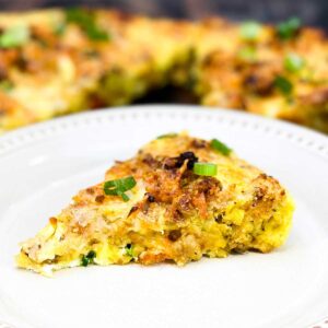 Slice of stuffing frittata on plate with remaining frittata in the background