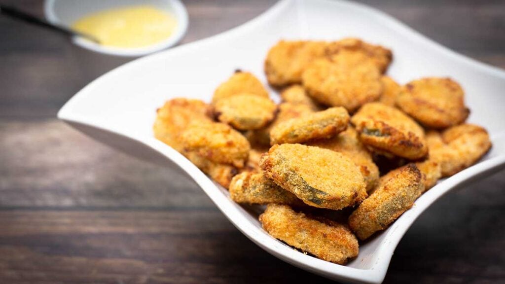 Air Fryer Fried Pickles in a white dish next to a mustard dipping sauce