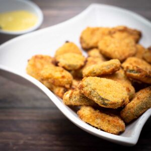 Air Fryer Fried Pickles in a white dish next to a mustard dipping sauce
