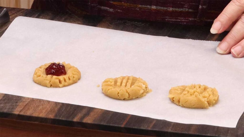 showing a jelly thumbprint cookie next to two traditional peanut butter cookies