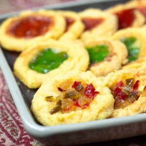 cheddar cheese thumbprint cookies on a tray with various toppings