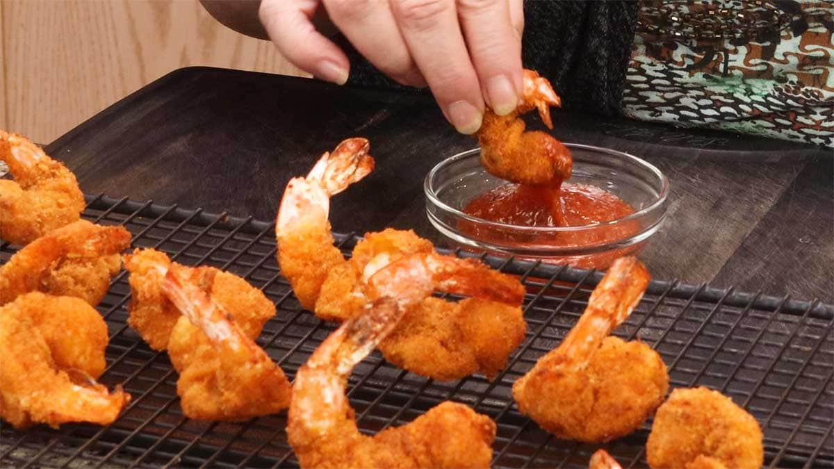 dipping air fryer fried shrimp into cocktail sauce