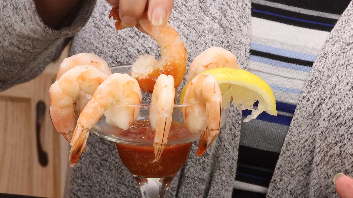 dipping shrimp into cocktail sauce
