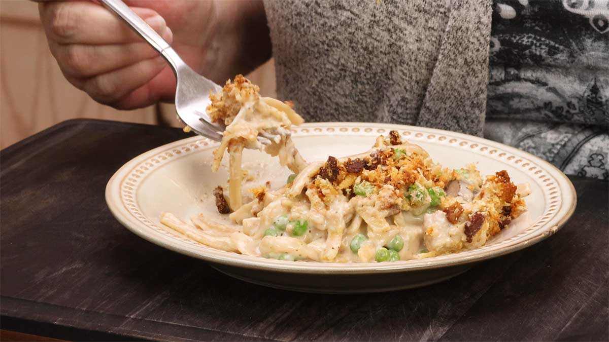 a scoop of turkey tetrazzini on a plate with a forkful being raised