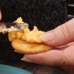 spreading cheese mixture on a cracker
