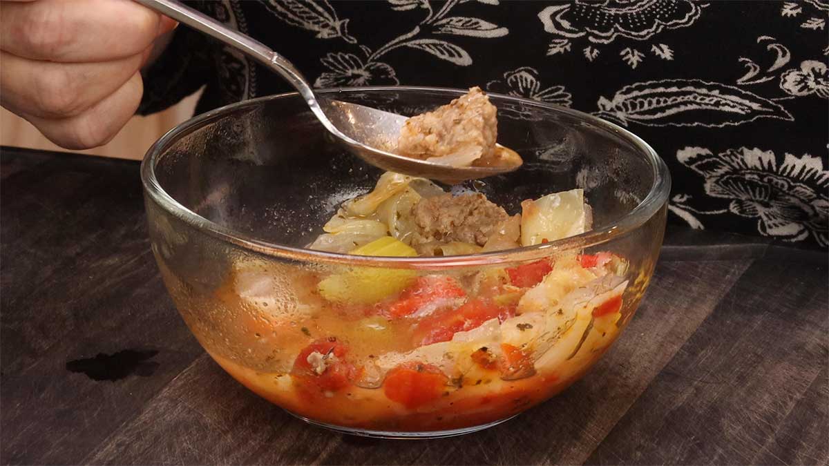 glass bowl of sausage and cabbage soup with spoon