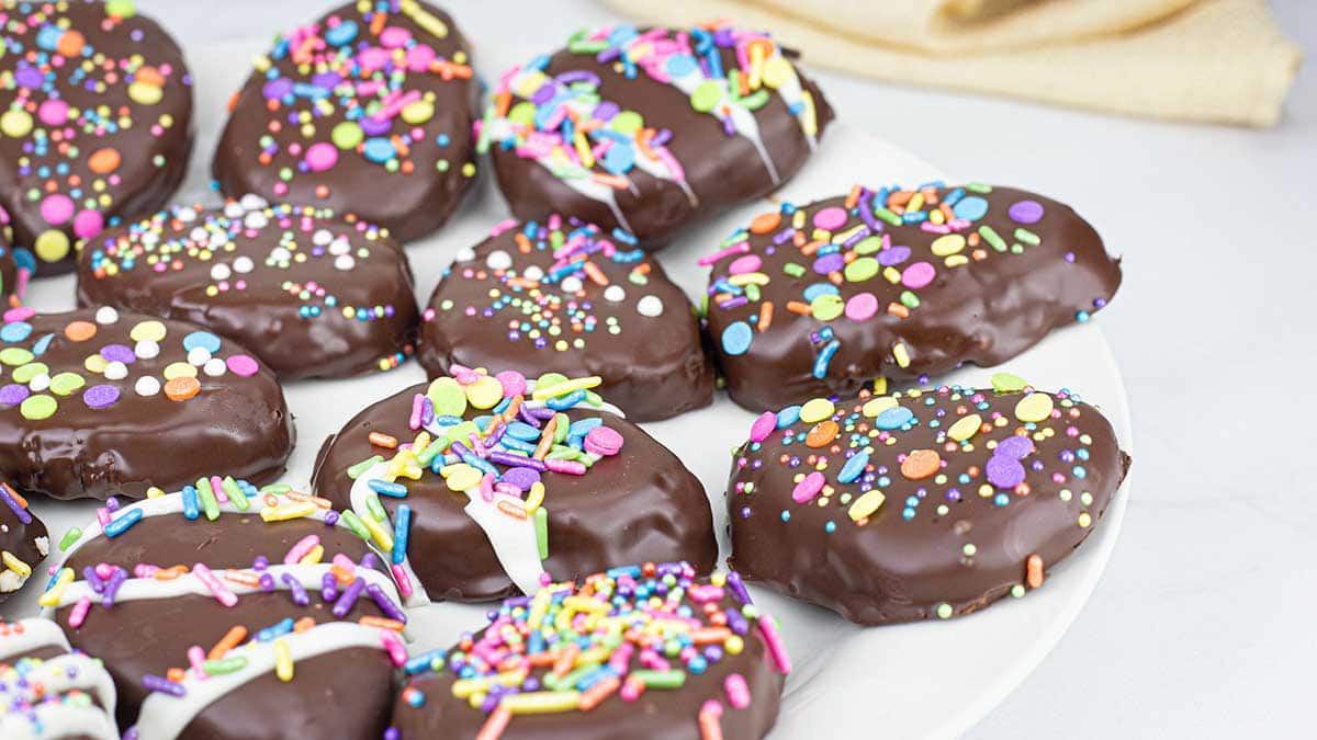 homemade peanut butter eggs on a white platter decorated in dark chocolate and pastel sprinkles for Spring.