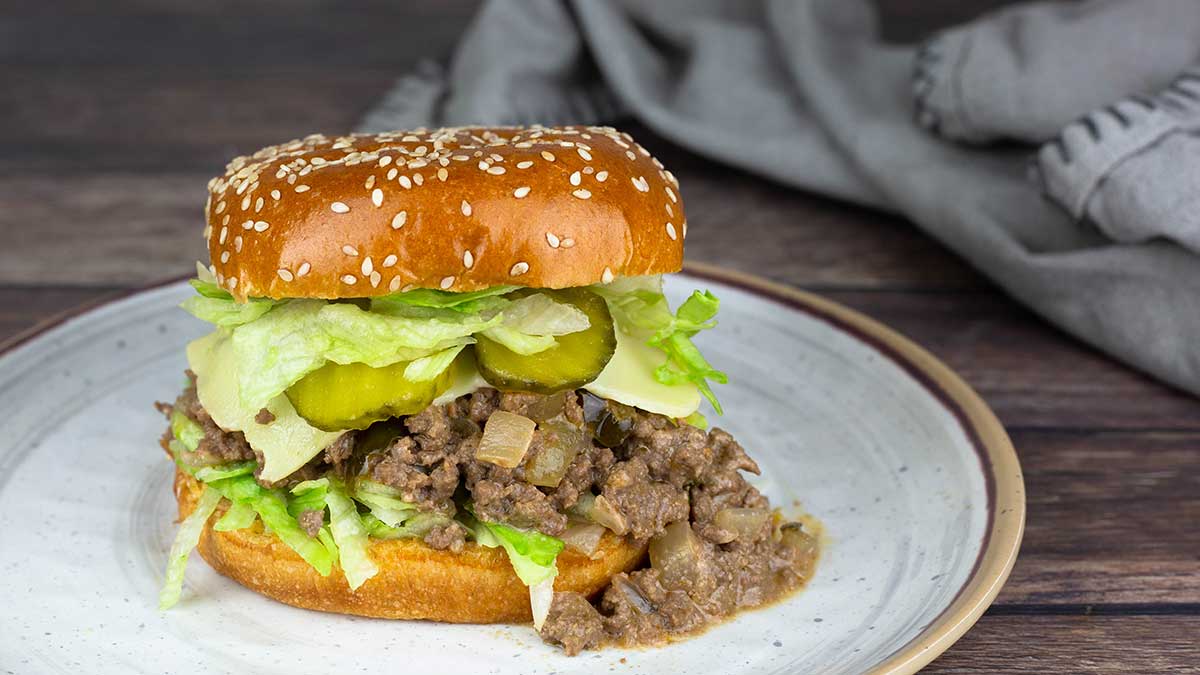 big mac sloppy joe on a plate with lettuce cheese and pickles. 