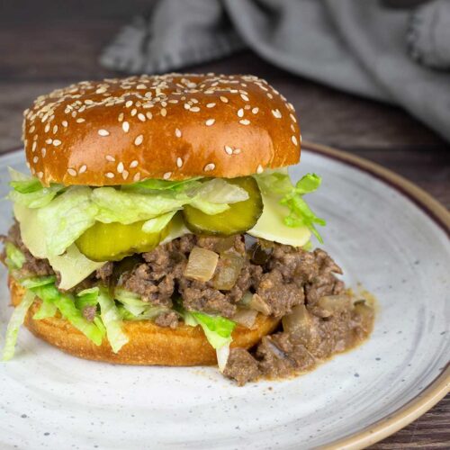 big mac sloppy joe on a plate with lettuce cheese and pickles.