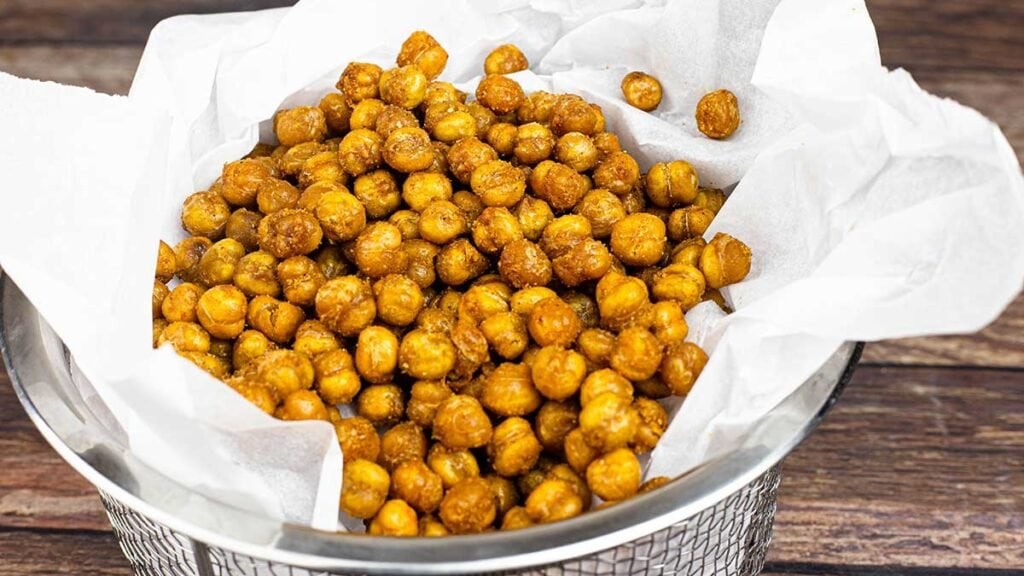 A basket of air fryer chickpeas with parchment paper.