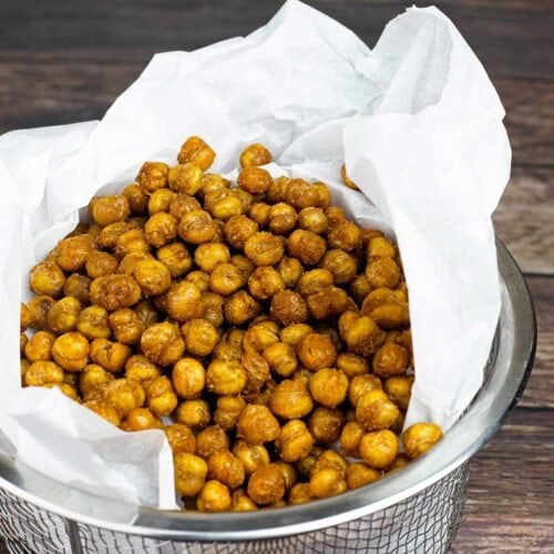 A basket of air fryer chickpeas with parchment paper.