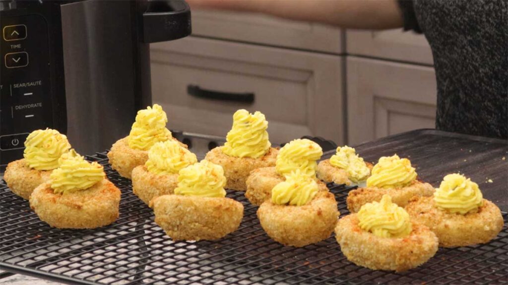 fried deviled eggs decorated on cooling rack.