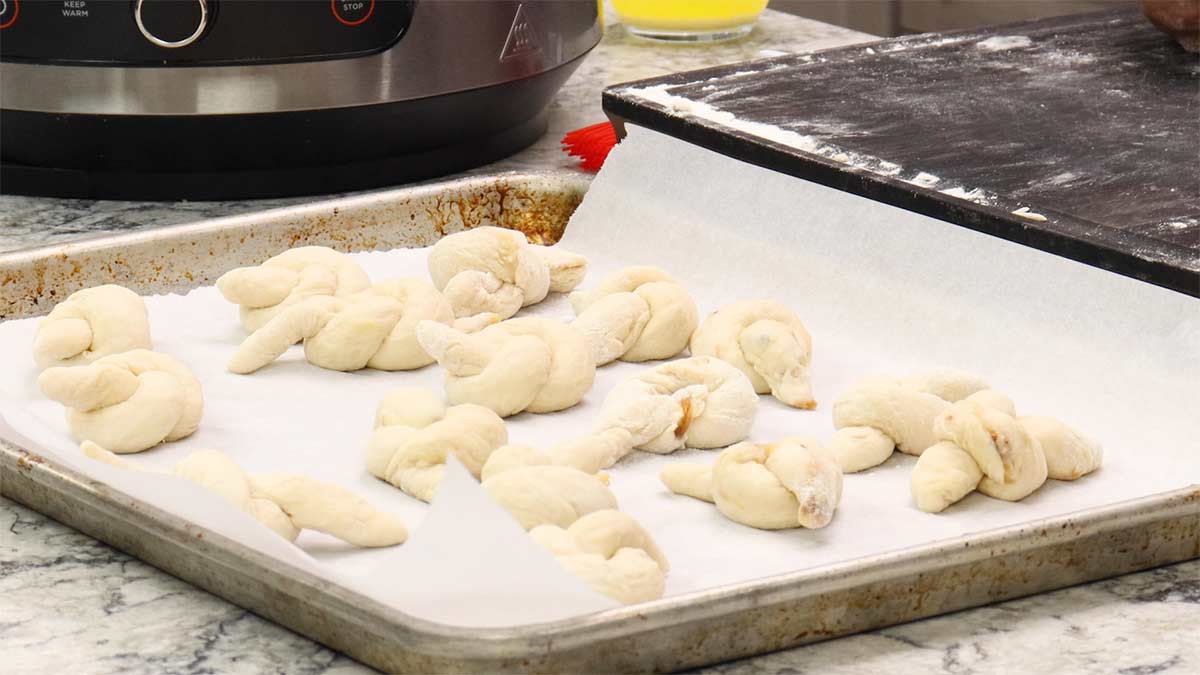 tied garlic knots on parchment lined tray.