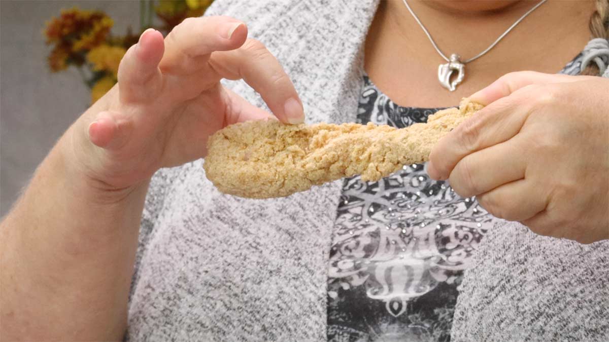 hand holding a breaded chicken strip.