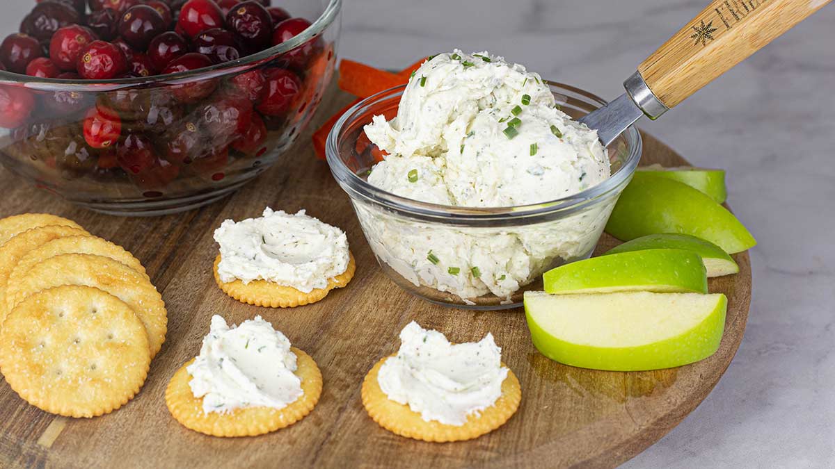 Garlic & Herb Spread in a bowl next to apples and crackers with the spread on them. 