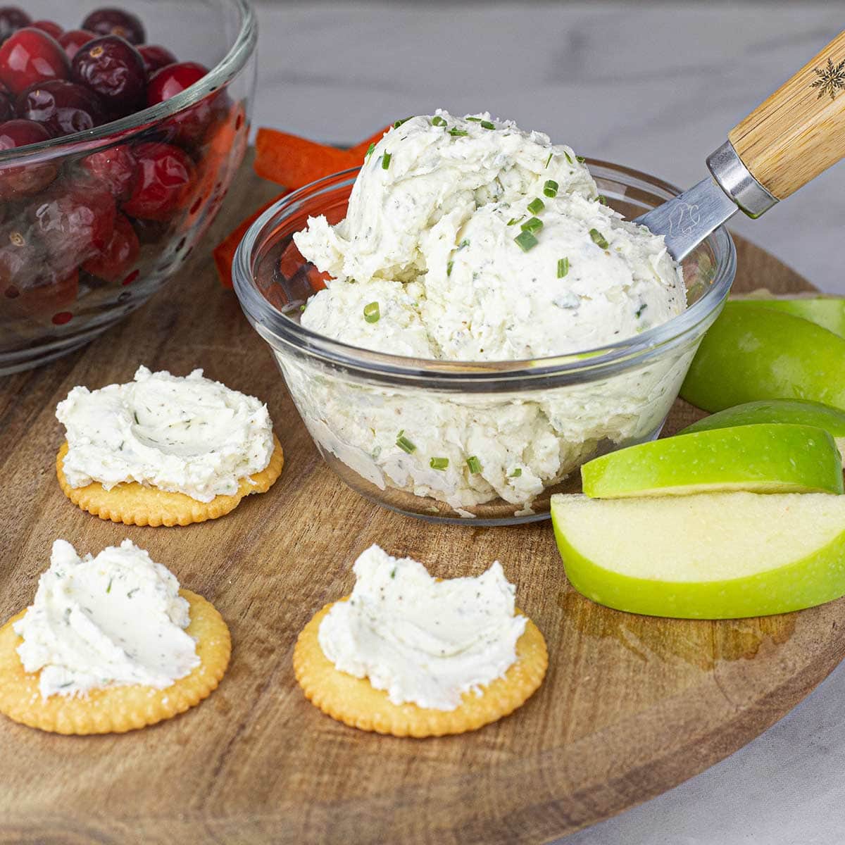 Garlic & Herb Spread in a bowl next to apples and crackers with the spread on them.