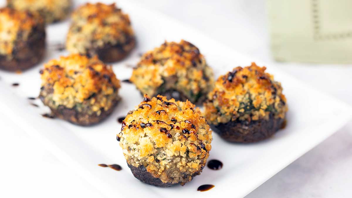 air fryer stuffed mushrooms with fig glaze drizzled on top on a plate.