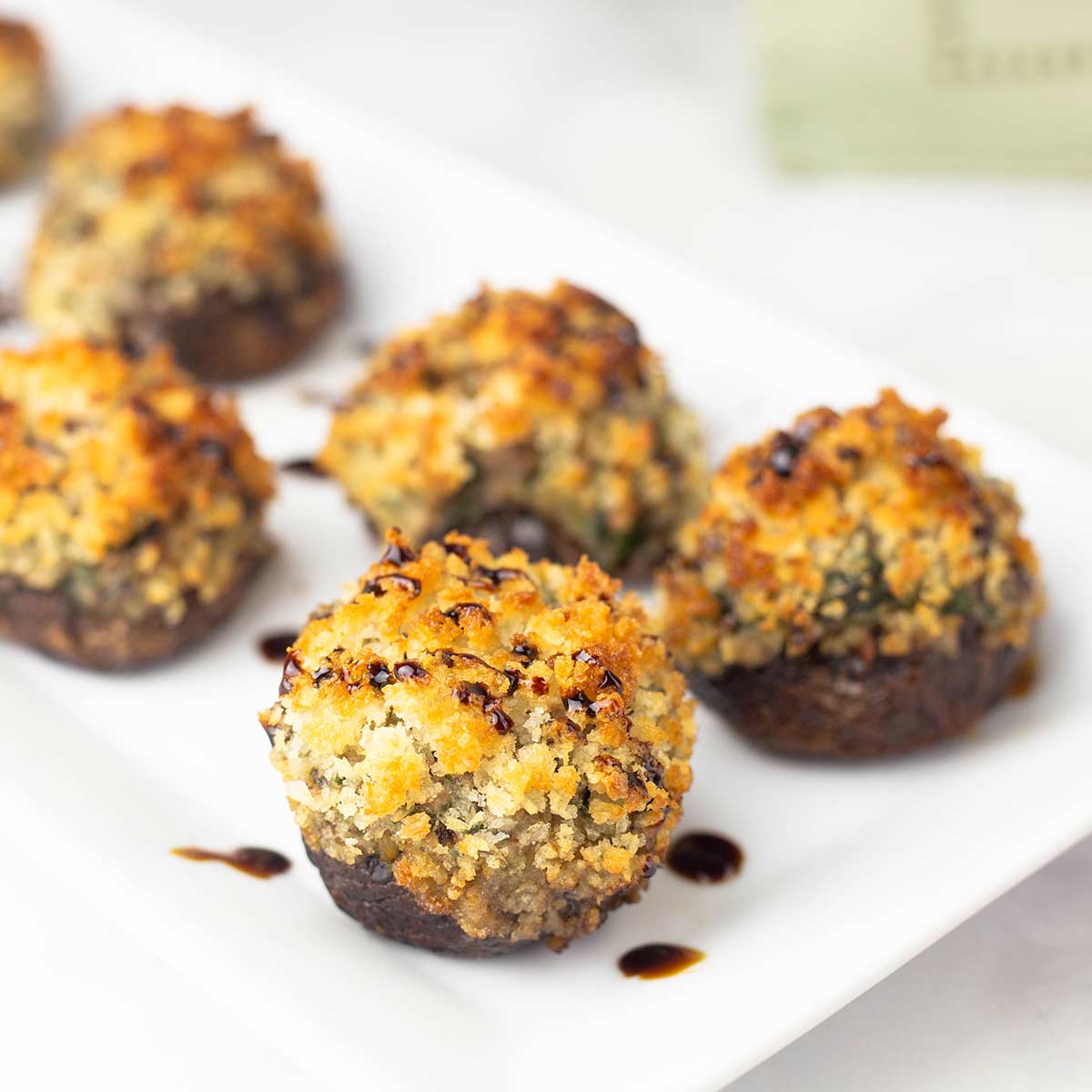 air fryer stuffed mushrooms with fig glaze drizzled on top on a plate.