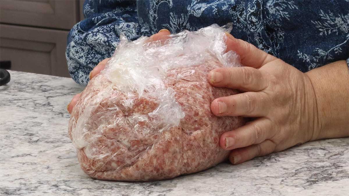 sausage wrapped turkey with plastic wrap ready to go into the freezer.
