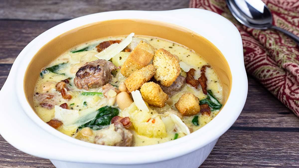 white bowl of zuppa toscana with croutons on top.