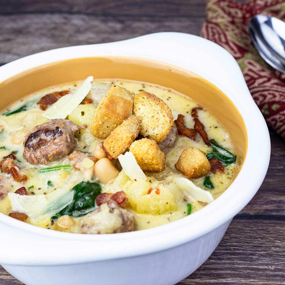 white bowl of zuppa toscana with croutons on top.