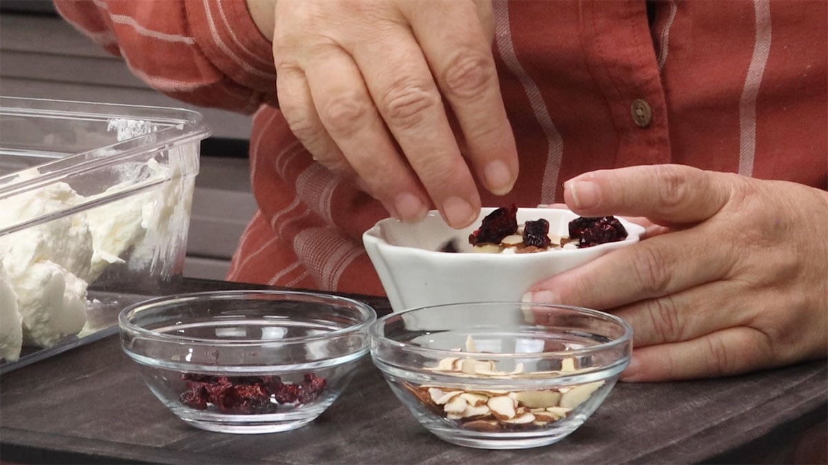 Adding dried cranberries and almonds to yogurt.