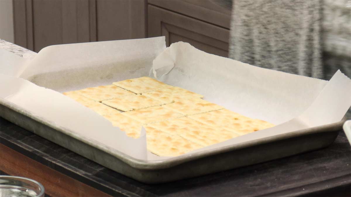 saltine crackers on parchment lined tray.