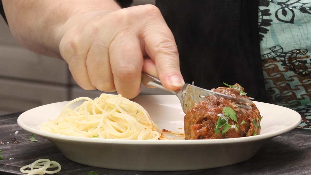 Cutting braciole with a fork to eat.