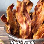 Ninja Foodi Bacon in a wire strainer standing up next to scrambled eggs.
