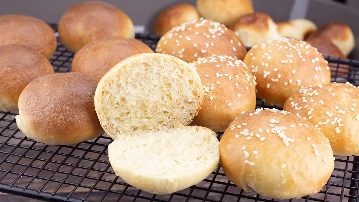 Brioche Slider Buns on table with one open to see the soft crumb.