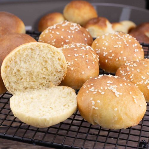 Brioche Slider Buns on table with one open to see the soft crumb.