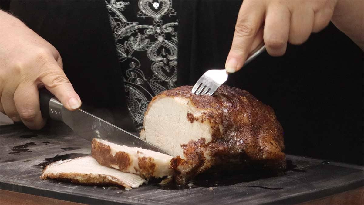 cutting thick slice of Ninja Foodi Pork Roast.
