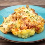 cauliflower steak with sauce and melted golden brown cheese on top on a blue plate.