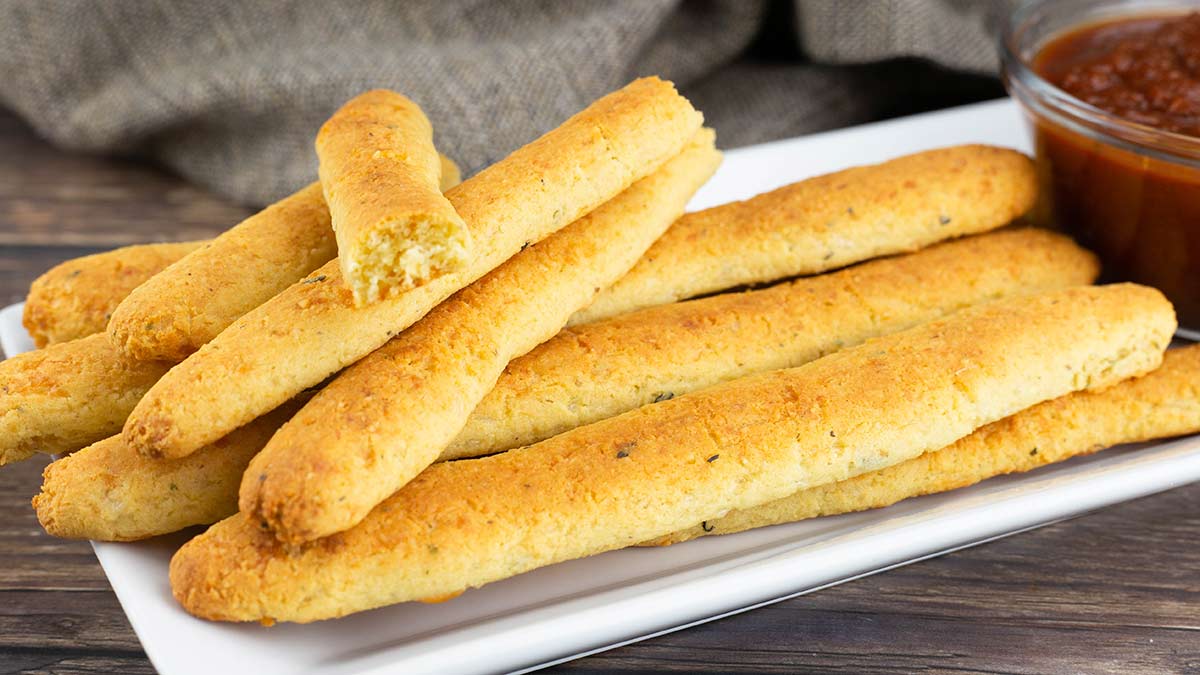 Keto breadsticks on a plate with marinara beside them.