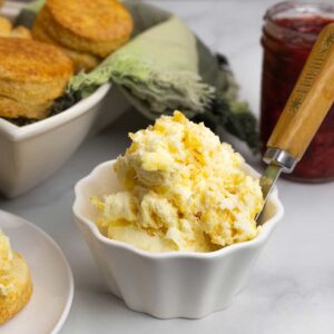 bowl of clotted cream beside scones in a basket.