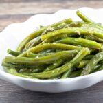 garlic butter green beans in a white serving bowl.