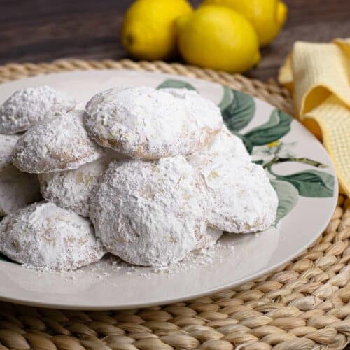 Lemon Cooler Cookies on a plate with Lemons in the background.