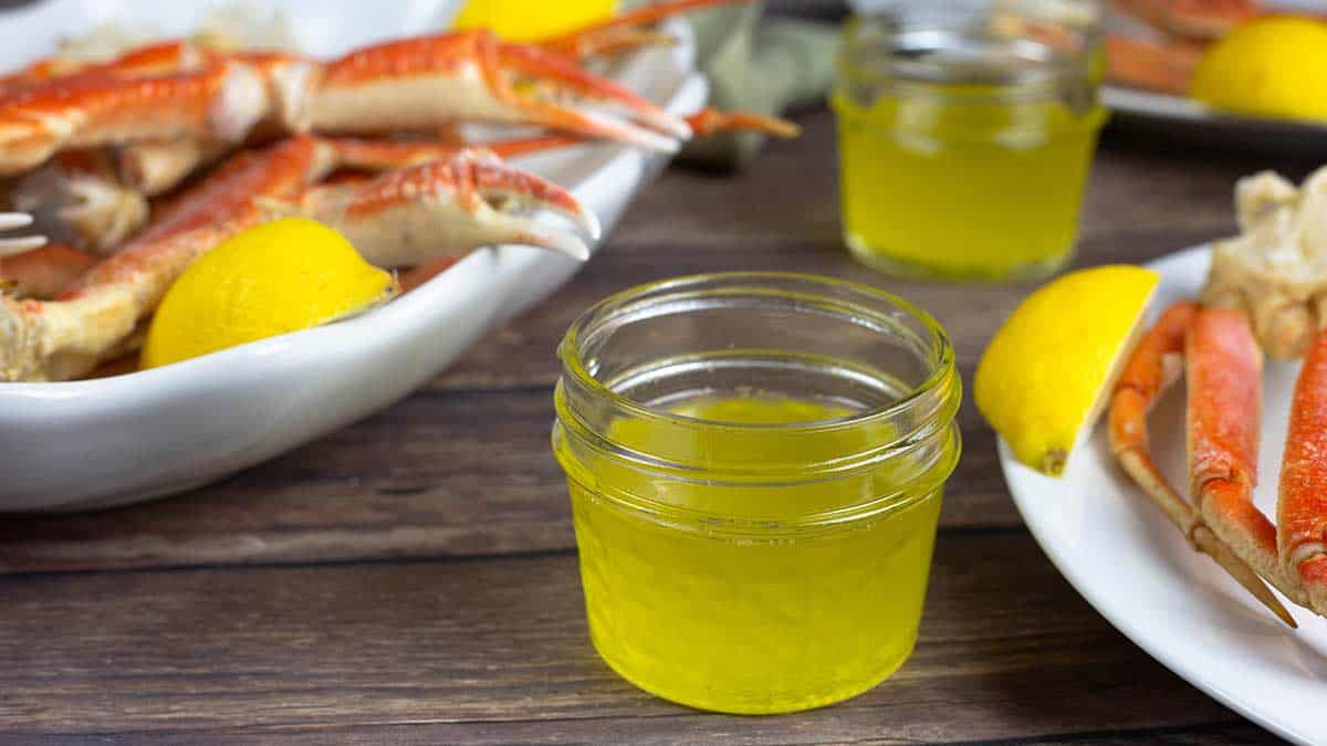 clarified butter in a small jar next to steamed crab legs.