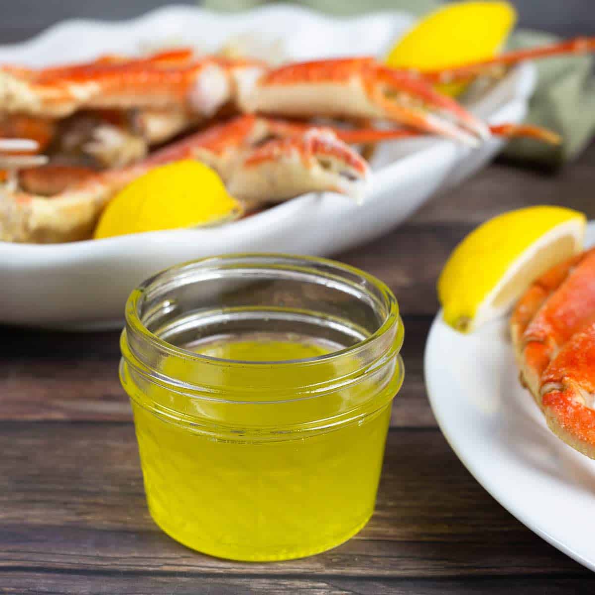 clarified butter in a small jar next to steamed crab legs.