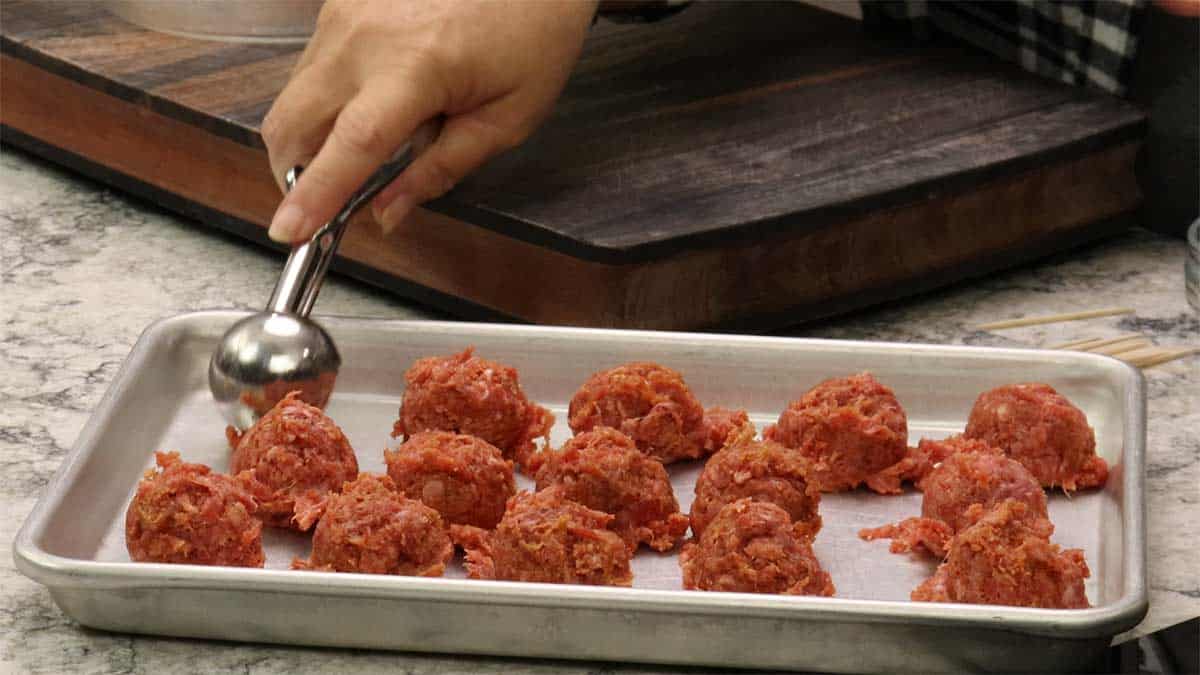 scooping the meatball mixture onto a tray. 