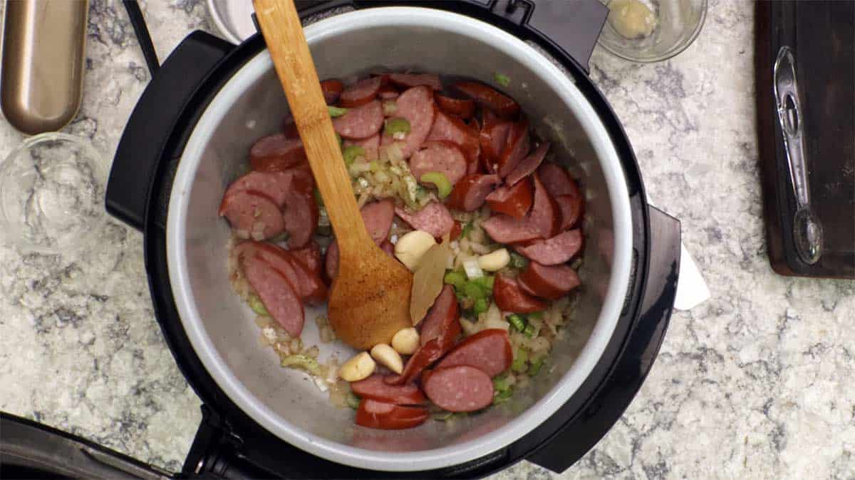 adding sausage, garlic, bay leaf to chowder and stirring.