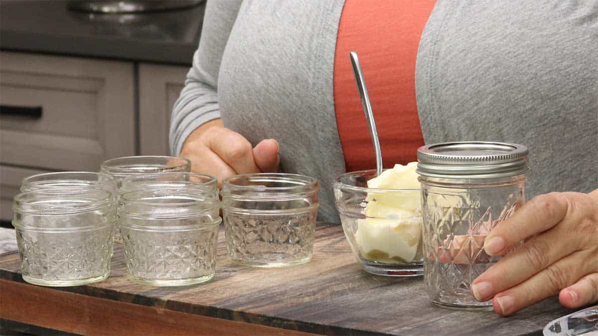 small canning jars with a bowl of butter next to them.