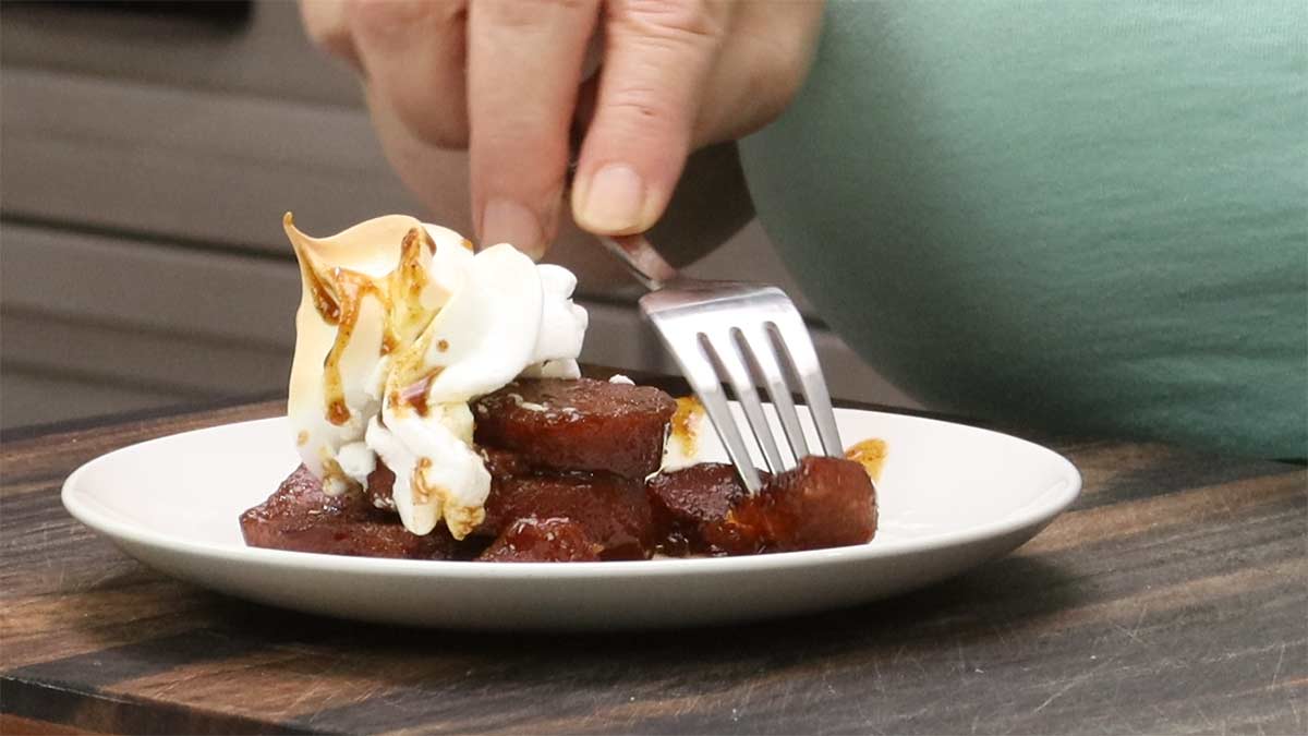 candied sweet potatoes on a white plate with a fork piercing one.