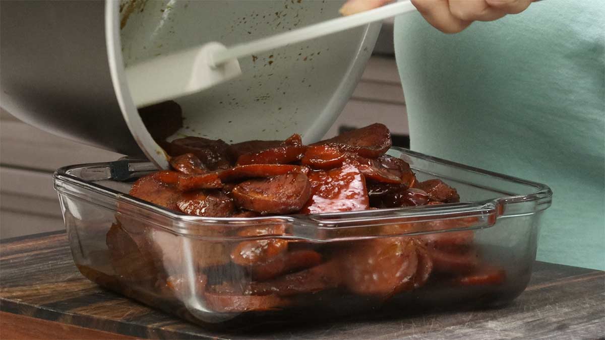 Transferring slow cooker candied sweet potatoes to a casserole dish.