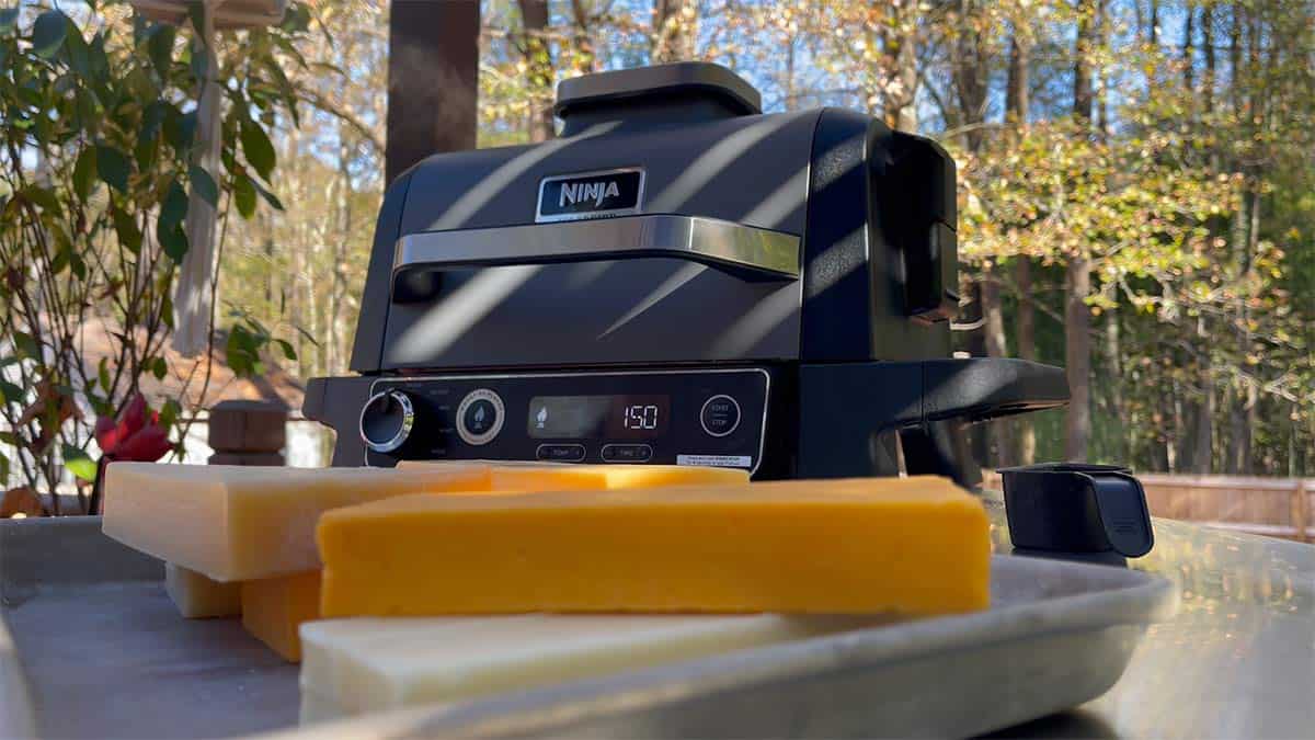 The Ninja Woodfire Grill with a tray of cheese beside it.