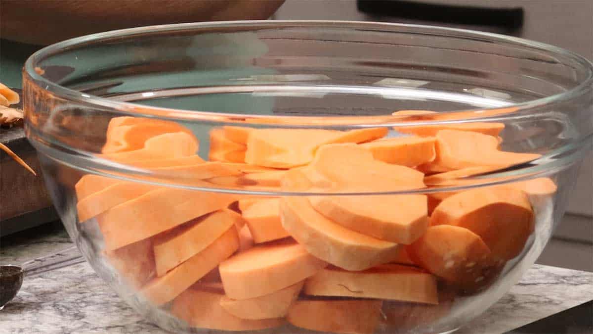 peeled and sliced sweet potatoes in a glass bowl. 