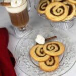 Cinnamon Roll Cookies on a round platter beside two plates of cookies and a cup of coffee.