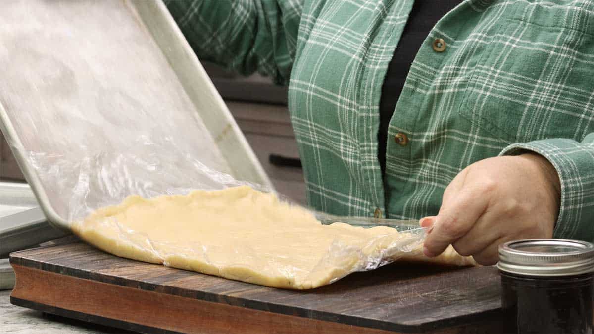 Moving the chilled dough from the tray to a flat surface.
